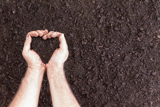 Hand holding soil in the shape of a heart
